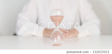 Woman with Hourglass on table office, Sand flowing through the bulb of Sandglass measuring the passing time. countdown, deadline, Life time and Retirement concept 132015015