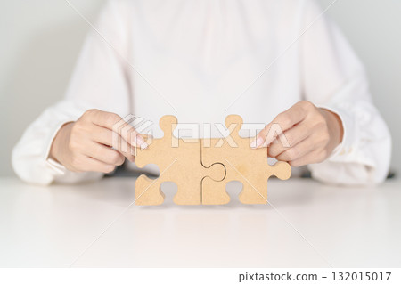 Woman connecting couple puzzle piece, wood jigsaw on table. Business solutions, mission, success, goals, strategy, Teamwork, Idea, Solution and challenge concepts Woman connecting couple puzzle piece, wood jigsaw on table. Business solutions, mission, success, goals, strategy, Teamwork, Idea, Solution and challenge concepts 132015017