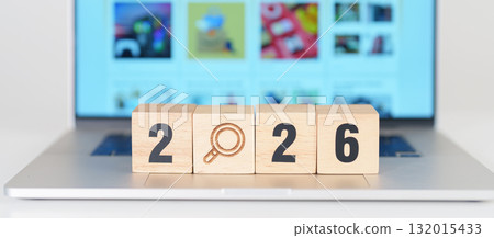 Happy New Year 2026 block magnifying glass icon against laptop background. Hiring, recruitment, job, jobless SEO, Search Engine Optimization and New Year concepts 132015433