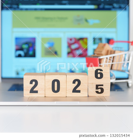 2025 end year to Happy New Year 2026 block with shopping trolley cart on table. E commerce, online shopping, finance, consumer economy and celebration concepts 132015434