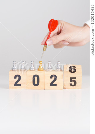 Hand holding red dart over people chess and 2026 year blocks. Goal, plan, action, target, strategy, leadership, New Year and marketing concept Hand holding red dart over people chess and 2026 year blocks. Goal, plan, action, target, strategy, leadership, New Year and marketing concept 132015453