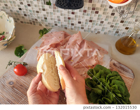 Anonymous person makes sandwich with sausage, lettuce, and mortadella, homemade mayonnaise in kitchen. Italian cuisine, high-quality farm-grown ingredients. Anonymous person makes sandwich with sausage, lettuce, and mortadella, homemade mayonnaise in kitchen. Italian cuisine, high-quality farm-grown ingredients. 132015530