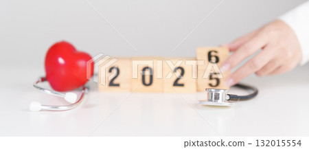 2025 end year to Happy New Year 2026 with Stethoscope of doctor and heart shape on table. health care, Insurance, Wellness and medical concepts 132015554