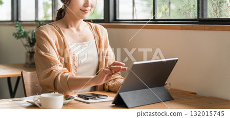 A woman working remotely while drinking coffee in a cafe A woman working remotely while drinking coffee in a cafe 132015745