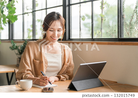 A woman working remotely while drinking coffee in a cafe A woman working remotely while drinking coffee in a cafe 132015749