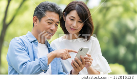 一對中年夫婦正在操作智慧型手機 一對中年夫婦正在操作智慧型手機 132016128