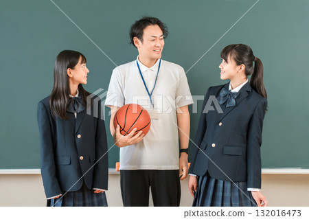 教室裡,黑板前,一位男老師拿著籃球,一位女學生穿著西裝 教室裡,黑板前,一位男老師拿著籃球,一位女學生穿著西裝 132016473