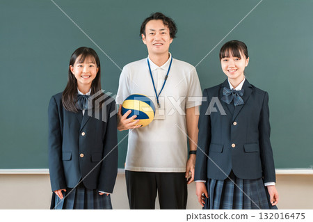 教室裡，一名男老師拿著排球，一名女學生穿著西裝站在黑板前 132016475