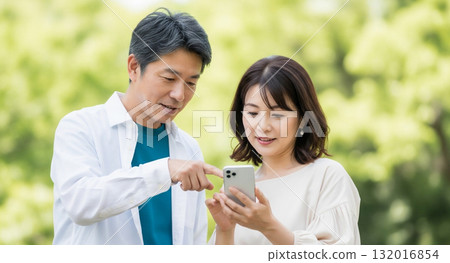 A middle-aged couple operating a smartphone A middle-aged couple operating a smartphone 132016854