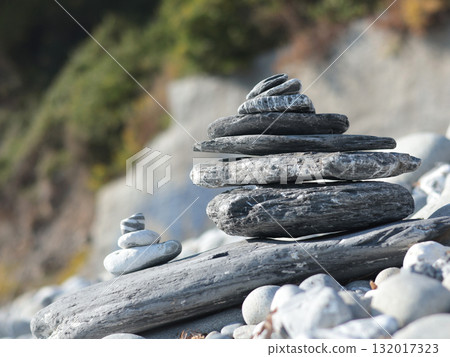 Big and small pyramid of marble stones against mountain backdrop on sunny day. Balance of mental health and meditation. Caring for body. Big and small pyramid of marble stones against mountain backdrop on sunny day. Balance of mental health and meditation. Caring for body. 132017323