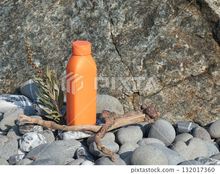 Plastic orange beauty bottle against backdrop of natural elements. Cosmetics and facial and hair care. Mock-up template for design. Eco-friendly products. Background, design composition. 132017360