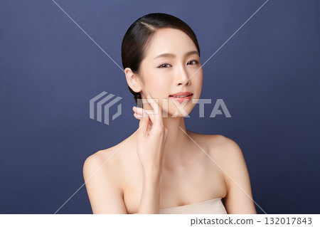 A beautiful young Asian woman with clean, fresh skin against a blue background. Skincare, facial treatment, cosmetology, beauty, and spa. An elegant portrait of an Asian woman. A beautiful young Asian woman with clean, fresh skin against a blue background. Skincare, facial treatment, cosmetology, beauty, and spa. An elegant portrait of an Asian woman. 132017843