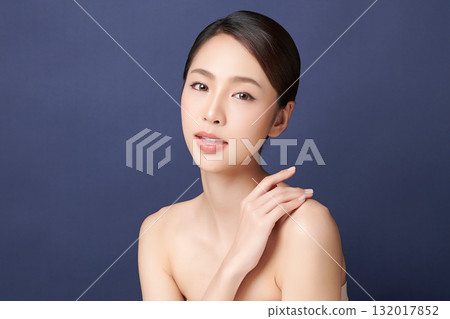 A beautiful young Asian woman with clean, fresh skin against a blue background. Skincare, facial treatment, cosmetology, beauty, and spa. An elegant portrait of an Asian woman. A beautiful young Asian woman with clean, fresh skin against a blue background. Skincare, facial treatment, cosmetology, beauty, and spa. An elegant portrait of an Asian woman. 132017852