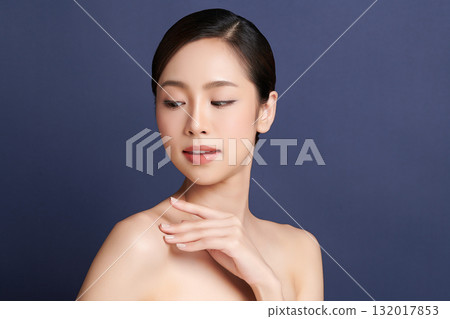 A beautiful young Asian woman with clean, fresh skin against a blue background. Skincare, facial treatment, cosmetology, beauty, and spa. An elegant portrait of an Asian woman. 132017853