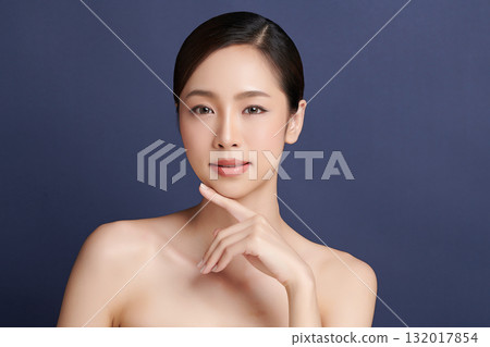 A beautiful young Asian woman with clean, fresh skin against a blue background. Skincare, facial treatment, cosmetology, beauty, and spa. An elegant portrait of an Asian woman. A beautiful young Asian woman with clean, fresh skin against a blue background. Skincare, facial treatment, cosmetology, beauty, and spa. An elegant portrait of an Asian woman. 132017854