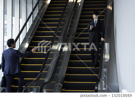 Businessman riding escalator 132018089