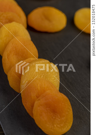 dried ripe orange apricot fruits on a black slate board, dried seedless pure dried apricots for long-term storage and used as a sweet or for making compotes dried ripe orange apricot fruits on a black slate board, dried seedless pure dried apricots for long-term storage and used as a sweet or for making compotes 132018475
