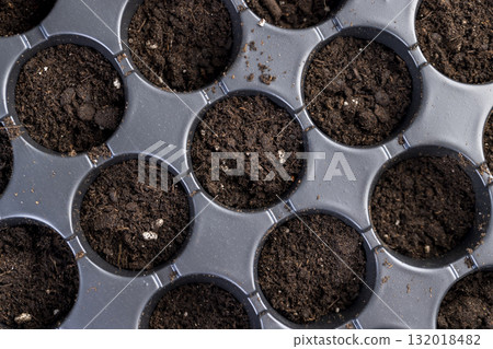 a plastic container with soil with a large number of round holes for growing seedlings, a black plastic tray for growing a large number of seedlings a plastic container with soil with a large number of round holes for growing seedlings, a black plastic tray for growing a large number of seedlings 132018482