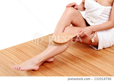 Woman is massaging skin on her legs with big brush, isolated on white background Woman is massaging skin on her legs with big brush, isolated on white background 132018798