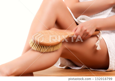 Woman with long slim legs doing peeling with a brush over white background 132018799
