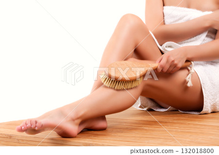 Woman with long slim legs doing peeling with a brush over white background Woman with long slim legs doing peeling with a brush over white background 132018800