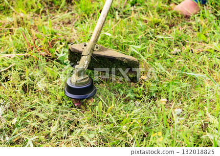 The gardener cutting grass with lawn mower. The gardener cutting grass with lawn mower. 132018825