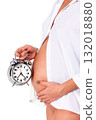 Closeup shot of pregnant woman who holds an alarm clock. Isolated on white background 132018880