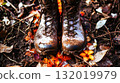 Muddy hiking boots resting on forest floor during spring season 132019979