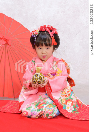 A girl in a kimono holding a ball and looking straight ahead 132020258