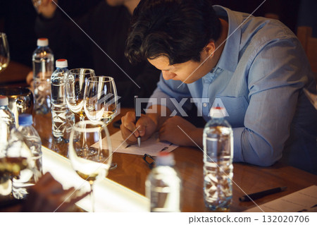 Sommelier Meticulously Evaluating Wine During an Indoor Tasting Event 132020706