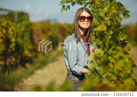 Woman Tending to Grapevines in Vineyard 132020711