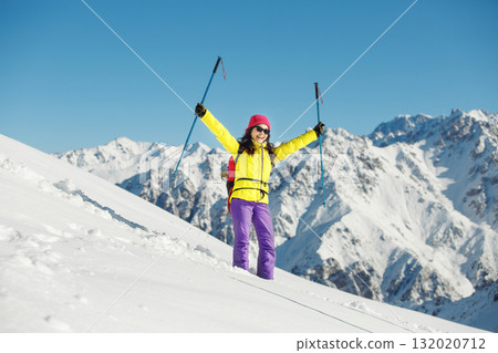 Joyful Female Mountaineer Celebrates Summiting Snowy Peak With Trekking Poles on Sunny Winter Day 132020712