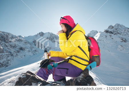 Woman in Vibrant Winter Gear Enjoying Hot Tea on Sunlit Mountain Summit During Clear Day Woman in Vibrant Winter Gear Enjoying Hot Tea on Sunlit Mountain Summit During Clear Day 132020713