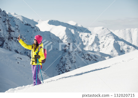 Active Sportswoman Taking Self-Portrait Against Snowy Mountain Backdrop Active Sportswoman Taking Self-Portrait Against Snowy Mountain Backdrop 132020715