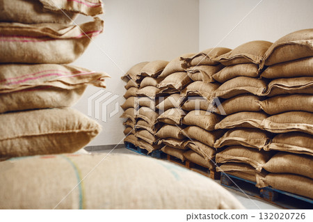 Neatly Stacked Jute Bags of Coffee in a Cool Storage Warehouse Neatly Stacked Jute Bags of Coffee in a Cool Storage Warehouse 132020726