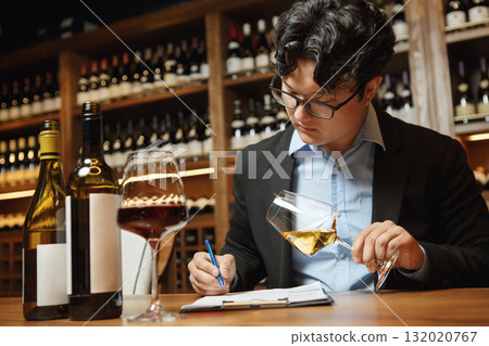 Sommelier Tasting White Wine While Taking Notes in Wine Cellar. Professional Wine Tasting and Evaluation Concept.  132020767