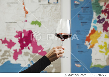 Female Hand Holding Glass of Red Wine in Front of Colorful Wine Map Female Hand Holding Glass of Red Wine in Front of Colorful Wine Map 132020777