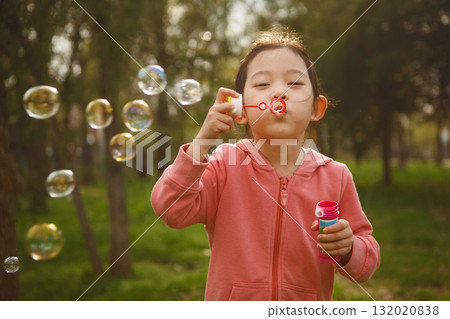 Little Girl Blowing Bubbles in Park 132020838