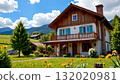A charming two story house with a brown wooden exterior, nestled in a lush green valley surrounded by mountains 132020981