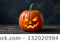 A carved pumpkin in the shape of a jack o' lantern sits on a surface 132020984