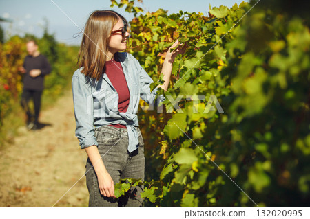 Woman Standing in Lush Green Field Near Vineyard Rows Woman Standing in Lush Green Field Near Vineyard Rows 132020995