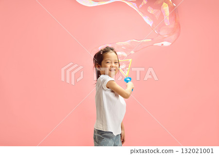 Lovely and Happy Little Girl Blowing Large Soap Bubble Around of Herself Standing on Pink Isolated Background Lovely and Happy Little Girl Blowing Large Soap Bubble Around of Herself Standing on Pink Isolated Background 132021001