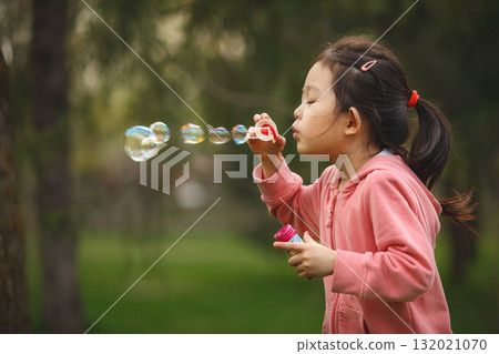 Young Girl Blowing Soap Bubbles in Park 132021070