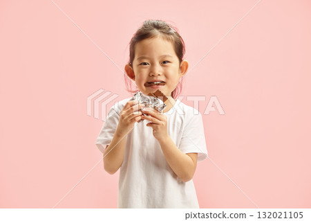 Happy Kid Girl Eating Greedily Big Chocolate Bar Isolated on Pink Background 132021105