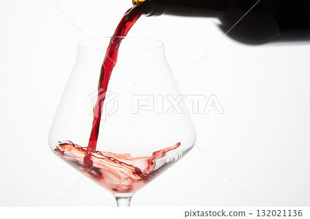 Red wine pouring into tilted wineglass from bottle. 132021136