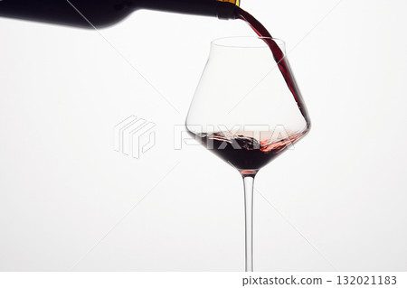 Red wine is poured from bottle into transparent glass. Red wine is poured from bottle into transparent glass. 132021183