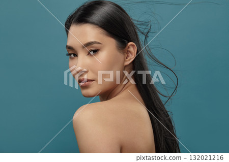 Well-groomed asian girl looking over shoulder to camera. 132021216