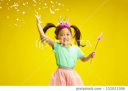 Joyful Little Child Princess with a crown and holding magic wand on Confetti Celebration. Joyful Little Child Princess with a crown and holding magic wand on Confetti Celebration. 132021306