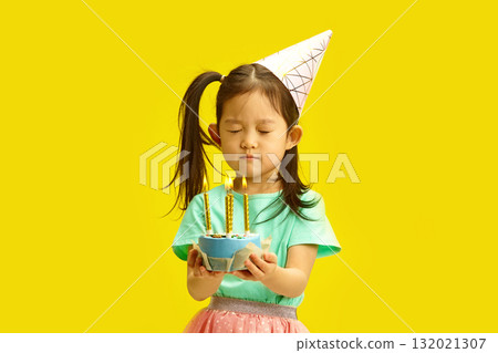 Five Year Old Little Girl with Eyes Closed, Making Wish on her Birthday, Holding Cake With lit Candles Standing on Yellow Background. Five Year Old Little Girl with Eyes Closed, Making Wish on her Birthday, Holding Cake With lit Candles Standing on Yellow Background. 132021307