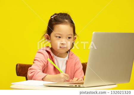 Studio portrait of Concentrated Asian Child in Distance Learning Session over isolated yellow. Young korean pupil Engages in Remote Study 132021320